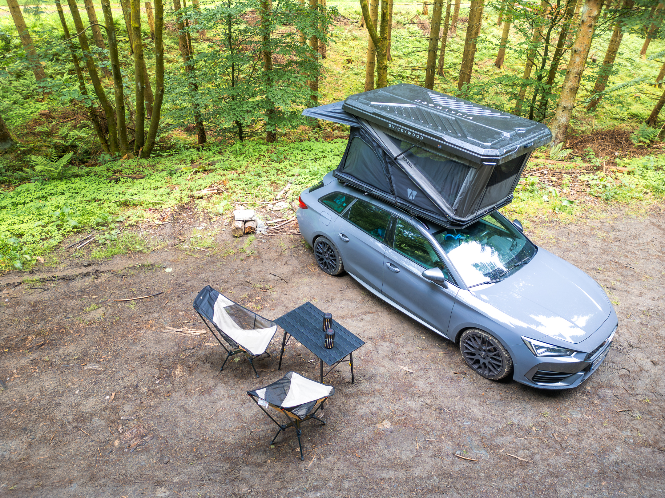 Dachzelt mit Tisch und Stühlen im Wald