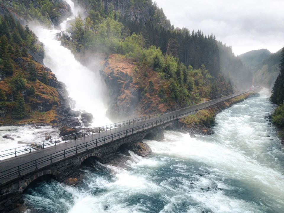 Waterfall above a bridge beside a rushing river